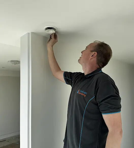 David Veeken adjusting a heat recovery ventilation vent in a modern residential home